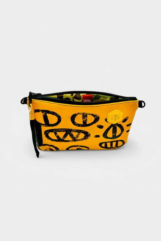 Model carrying the yellow Pouch No. 007, featuring black hand-painted graphics and a raised honeycomb monogram.
